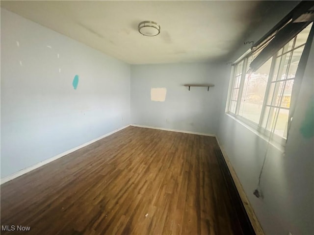 spare room featuring baseboards and wood finished floors