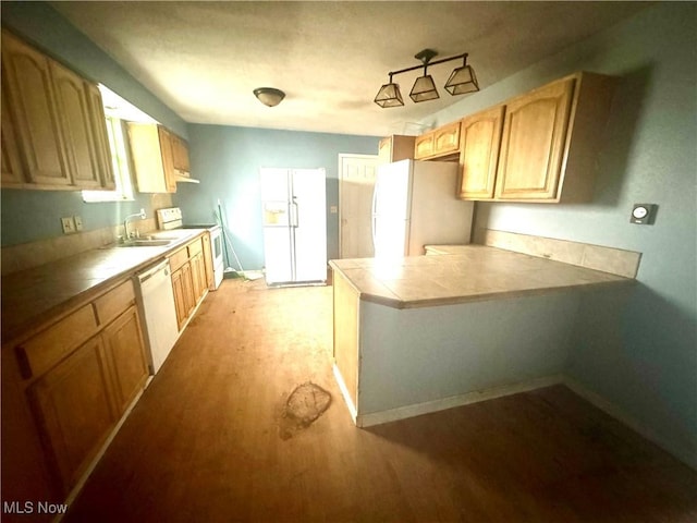 kitchen with light wood-style flooring, a sink, tile countertops, white appliances, and a peninsula