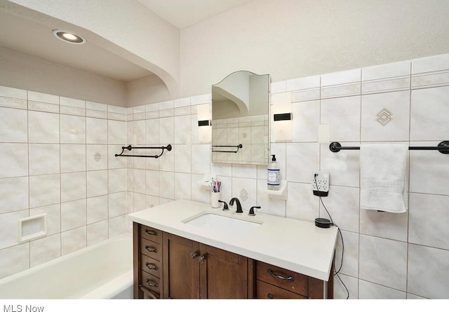 bathroom with vanity, tile walls, a bathtub, and backsplash