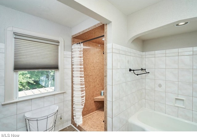 bathroom with curtained shower, tile walls, and a washtub