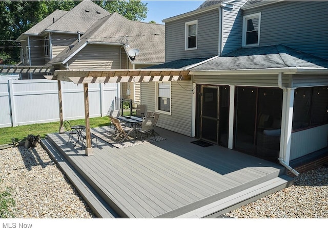 wooden deck with outdoor dining area, a sunroom, a pergola, and fence