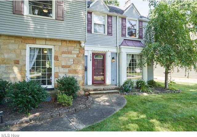 property entrance with a yard and stone siding