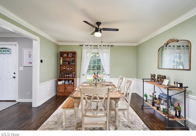 dining room featuring ornamental molding, wood finished floors, wainscoting, and ceiling fan