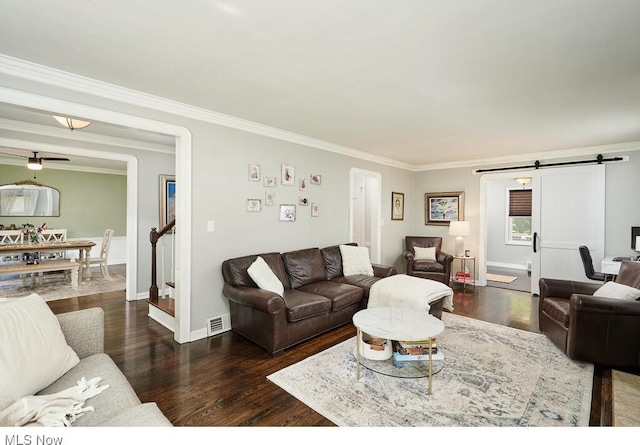 living area with visible vents, ornamental molding, stairs, dark wood-type flooring, and a barn door