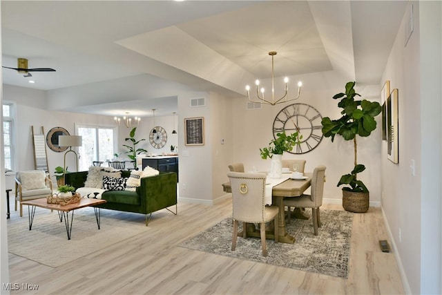 dining space featuring visible vents, ceiling fan with notable chandelier, light wood-type flooring, and baseboards