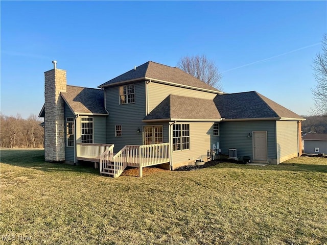 back of house featuring a yard, a deck, a chimney, and a shingled roof