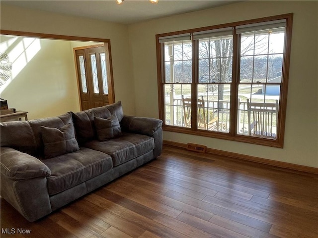 living area featuring visible vents, baseboards, and wood finished floors