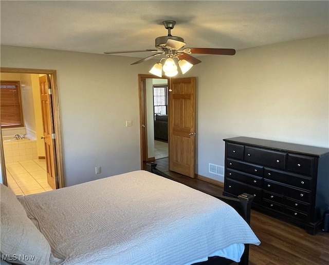 bedroom with visible vents, ensuite bathroom, dark wood finished floors, baseboards, and ceiling fan