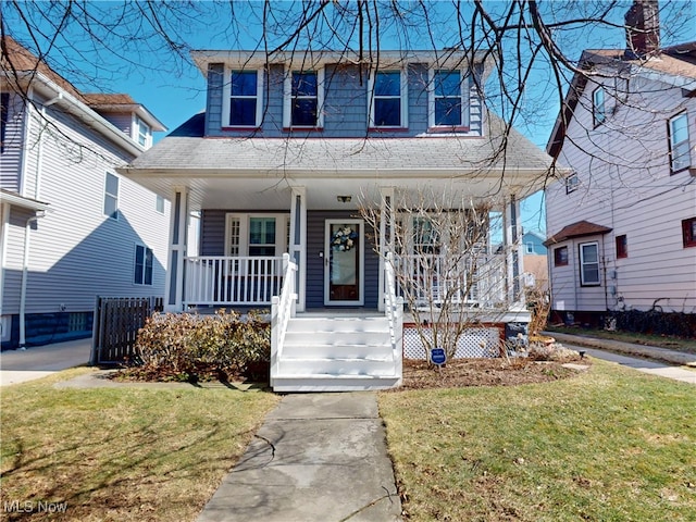 view of front facade with a porch, a shingled roof, and a front yard