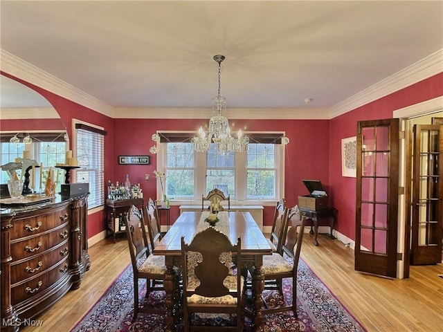 dining space featuring a wealth of natural light, an inviting chandelier, crown molding, and light wood-style floors