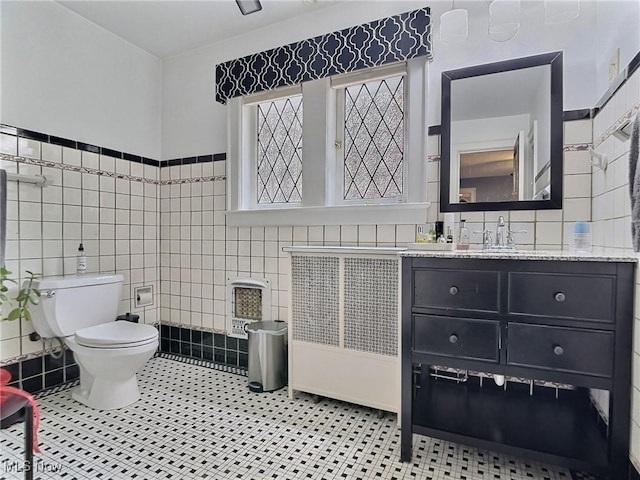 bathroom with tile patterned flooring, heating unit, toilet, and tile walls