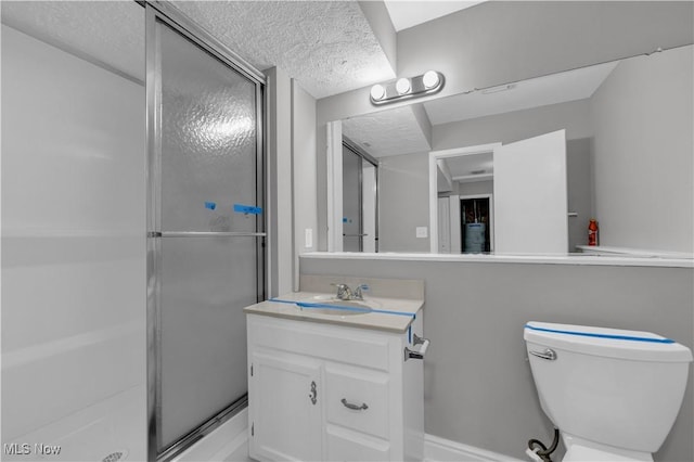 full bath featuring vanity, toilet, a shower stall, and a textured ceiling