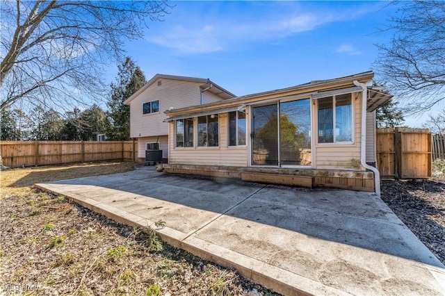 rear view of property featuring central AC unit, a fenced backyard, and a patio area