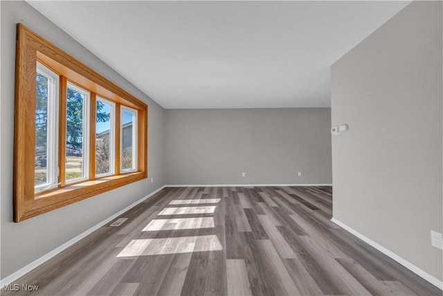 unfurnished room with visible vents, baseboards, and dark wood-type flooring