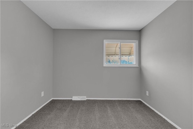 unfurnished room featuring visible vents, baseboards, and dark colored carpet