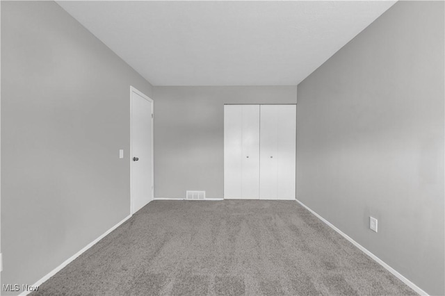 unfurnished bedroom featuring carpet flooring, visible vents, a closet, and baseboards