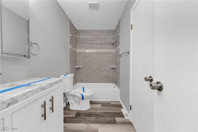 full bath featuring vanity, wood finished floors, visible vents, shower / tub combination, and toilet