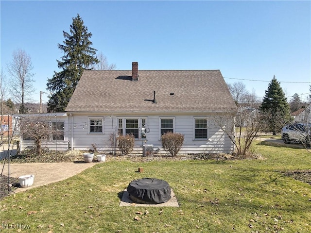 back of property featuring a yard, roof with shingles, and a chimney