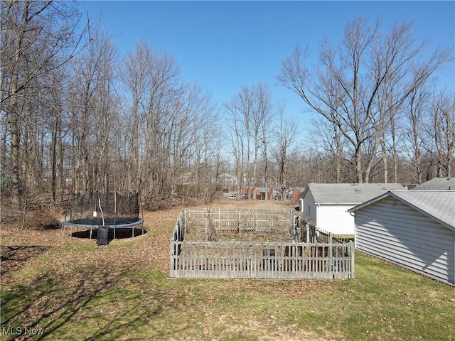 view of yard featuring fence, a trampoline, and a garden