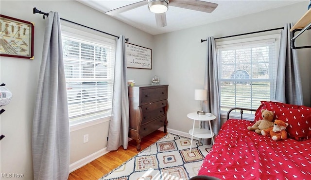 bedroom with a ceiling fan, wood finished floors, and baseboards