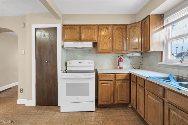 kitchen featuring under cabinet range hood, brown cabinets, and white electric range oven