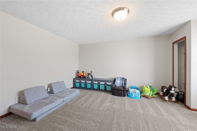 recreation room featuring baseboards, carpet floors, and a textured ceiling