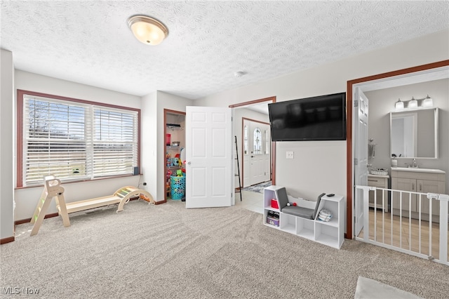 playroom with carpet, baseboards, and a textured ceiling