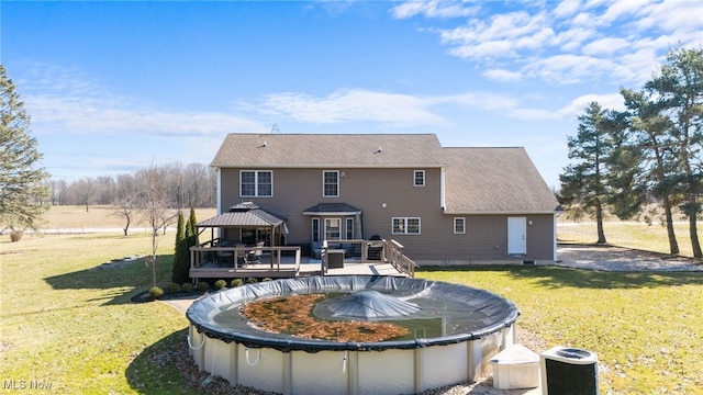 rear view of house featuring a gazebo, a lawn, and a deck