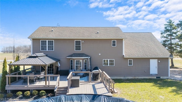 back of property featuring a yard, a deck, and a shingled roof