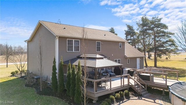 rear view of property featuring a gazebo, a yard, a wooden deck, and a shingled roof