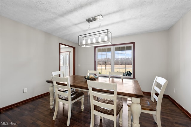 dining area featuring a textured ceiling, baseboards, and wood finished floors