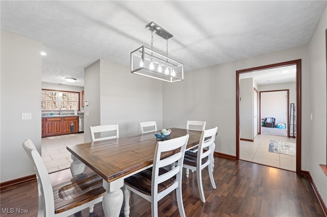 dining area with an inviting chandelier, a textured ceiling, baseboards, and wood finished floors