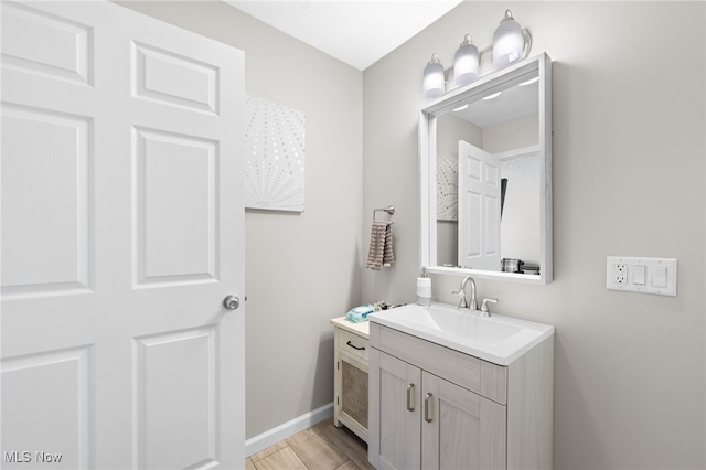 bathroom featuring vanity, baseboards, and wood finished floors