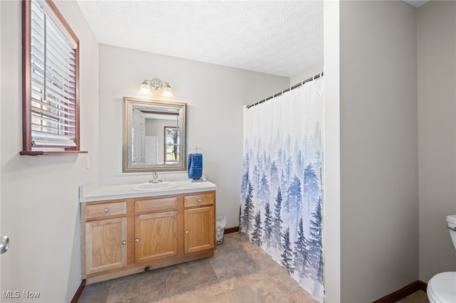 full bathroom with baseboards, toilet, vanity, a shower with curtain, and a textured ceiling