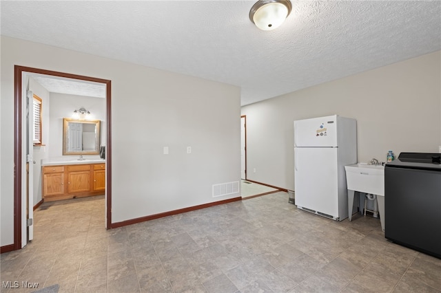 interior space featuring washer / clothes dryer, baseboards, visible vents, and freestanding refrigerator