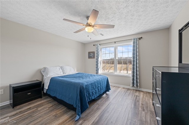 bedroom with visible vents, a ceiling fan, a textured ceiling, wood finished floors, and baseboards