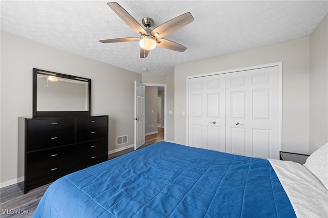 bedroom with visible vents, a textured ceiling, wood finished floors, a closet, and baseboards