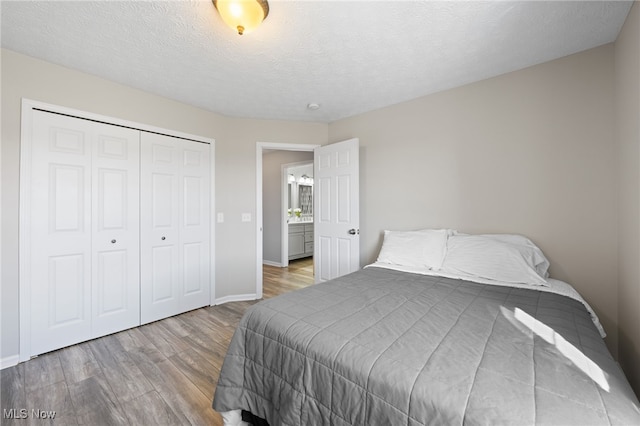 bedroom with baseboards, wood finished floors, a closet, and a textured ceiling