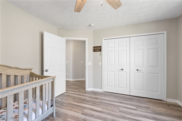 bedroom with ceiling fan, light wood-style floors, a closet, and baseboards