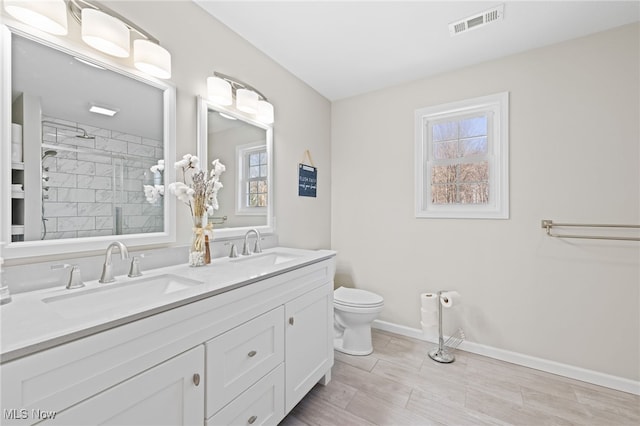 full bathroom featuring a sink, visible vents, tiled shower, and baseboards