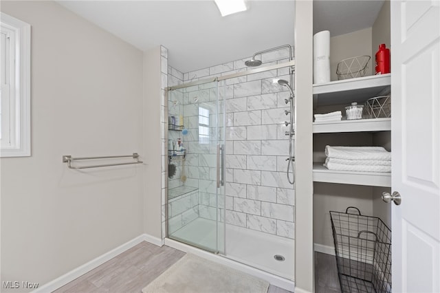 full bathroom featuring wood finished floors, baseboards, and a stall shower