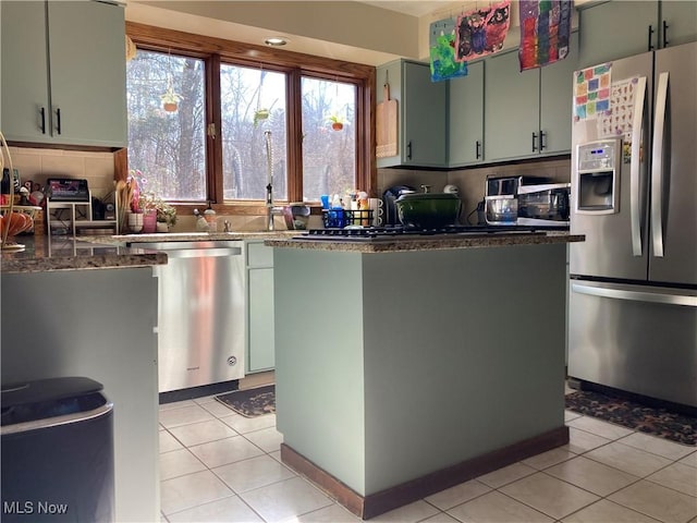 kitchen featuring light tile patterned floors, decorative backsplash, appliances with stainless steel finishes, and dark stone counters