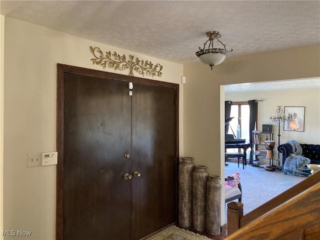 entryway with carpet and a textured ceiling