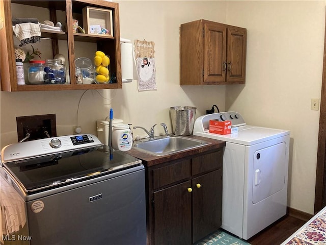 clothes washing area featuring separate washer and dryer, cabinet space, baseboards, and a sink