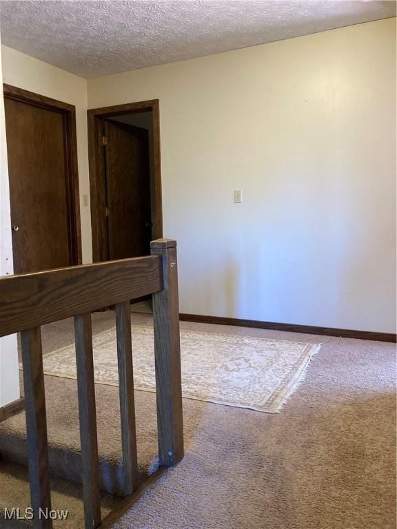 interior space featuring carpet, baseboards, and a textured ceiling