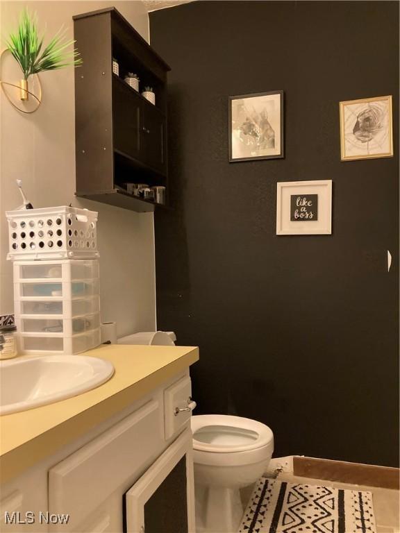 half bathroom with tile patterned floors, toilet, and vanity