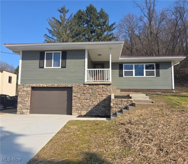 view of front of house featuring stone siding, a garage, and driveway