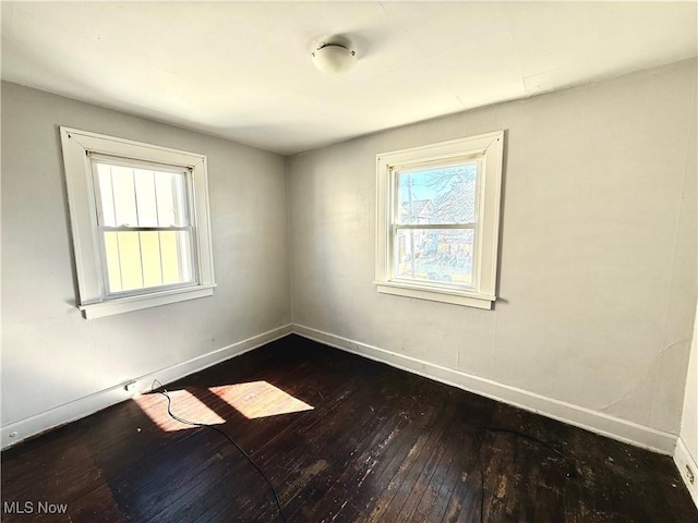 unfurnished room featuring baseboards and dark wood-style flooring