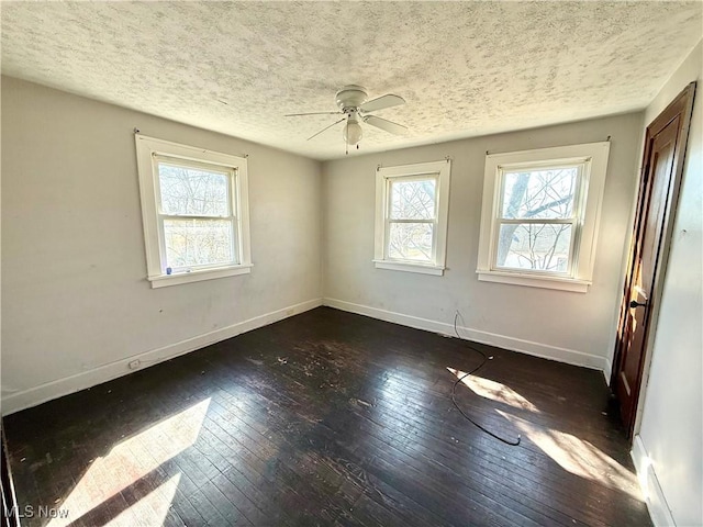 unfurnished room with ceiling fan, dark wood-type flooring, baseboards, and a textured ceiling