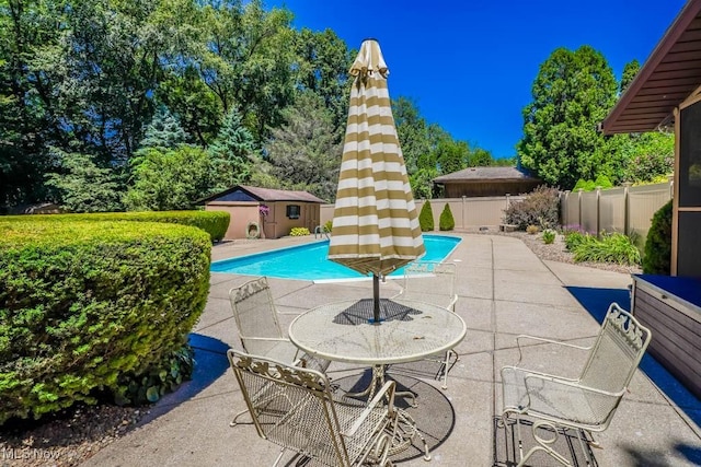 view of pool with a patio area, a fenced in pool, an outdoor structure, and a fenced backyard